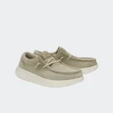 Mocasín Hey Dude modelo Wally Comf Suede, color camel o beige claro, confeccionado en gamuza con costuras visibles en el empeine. Posee un sistema de cordones elásticos y una suela gruesa y elevada de color crema.
