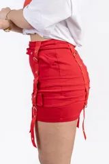 Minifalda negra con tres hileras de correas ajustables con hebillas plateadas.