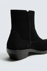 Bota estilo cowboy de caña media, confeccionada en piel con acabado de serraje. Presenta horma cuadrada, cierre lateral mediante cremallera y suela con tacón bajo.