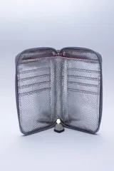 Billetera chica de cuero negro con textura tipo cocodrilo, cierre exterior, bolsillo para monedas con cierre en la parte trasera, múltiples ranuras para tarjetas y billetes, y forro rojo.