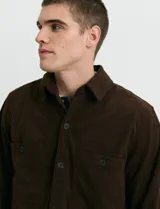 Sobrecamisa de pana color marrón, con manga larga, cierre frontal con botones y dos bolsillos frontales con solapa y botón.