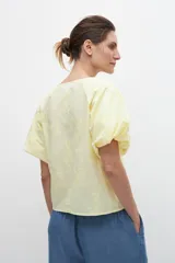 Blusa amarilla con estampado floral, mangas cortas abullonadas y cuello redondo.