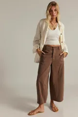 Pantalón chino de algodón marrón, de tiro alto y pierna ancha estilo wide-leg, con largo al tobillo, bolsillos laterales y cierre frontal.