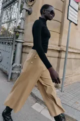 Pantalón tipo culotte de tiro alto, con pernera ancha y corta. Presenta detalles de botones dorados decorativos en la parte frontal y cierre lateral con cremallera oculta.