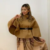 Capa corta negra de paño italiano con cuello alto y cinturón con hebilla dorada.