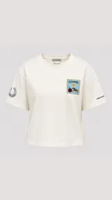 Remera de algodón premium color crema, con corte holgado y cuello redondo. Presenta un bordado en el pecho con diseño de estampilla que incluye un sol, un mate y un caballo, además de un bordado de herradura en la manga derecha.