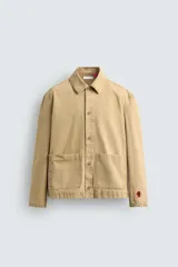 Sobrecamisa de corte relajado confeccionada en tejido de algodón con estructura canvas. Presenta cuello solapa, manga larga, cierre frontal con botones y dos bolsillos frontales de plastrón. Incluye un pequeño bordado a contraste en una de las mangas.