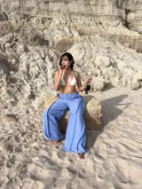 Pantalón ancho de tiro alto, color celeste claro, con costuras visibles en contraste que recorren verticalmente las piernas.