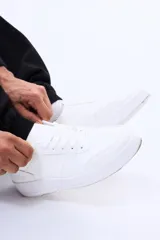 Championes urbanos de diseño minimalista en color blanco, con cordones al tono y suela de goma plana. Presentan perforaciones decorativas en la puntera y costuras reforzadas en los laterales.