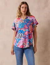 Blusa estampada con motivos florales en tonos rosa, azul y naranja. Tiene cuello en V y mangas cortas con volados.