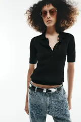 Jersey de punto semitransparente color negro, con cuello polo, manga corta y cierre frontal de botones.