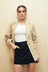 Short pollera color marrón de tiro alto, confeccionado en algodón. Presenta solapa frontal que simula una falda y bolsillos delanteros.