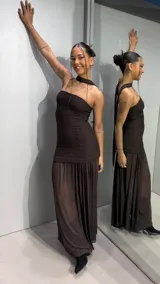 Vestido largo color marrón de silueta ajustada con diseño strapless y tiras cruzadas al cuello, confeccionado en tejido texturizado con falda larga semitransparente.
