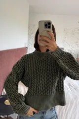 Sweater de tejido de punto con diseño de ochos en relieve, color gris oscuro con detalles en negro. Presenta cuello redondo alto y puños y ruedo acanalados.