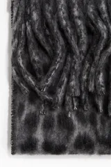 Bufanda de tejido suave con acabado cepillado, diseño con estampado de leopardo en tonos grises y negros, y flecos en los extremos.