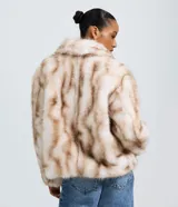 Saco corto de pelo sintético con estampa abstracta en tonos beige y marrón. Presenta cuello tipo solapa, mangas largas y cierre frontal, con una textura suave y voluminosa.