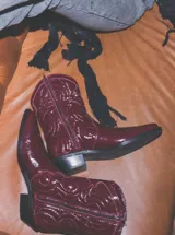 Bota corta tipo texana en cuero acharolado con punta afinada y taco bajo.