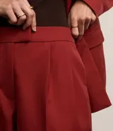 Pantalón de vestir color borgoña, de corte zanahoria, con pliegues delanteros, cierre con solapa y cremallera oculta.