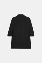 Blazer negro con cuello solapa con muescas, hombreras y forro interior a tono. Presenta manga por debajo del codo con detalle de drapeado y falsos bolsillos de vivo en el delantero, con cierre frontal de un solo botón dorado.