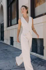 Pantalón de tiro medio, pierna ancha, confeccionado en tejido texturado de color claro con hilo metalizado. Presenta falsos bolsillos delanteros con botones metálicos dorados.