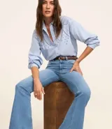 Pantalón flare de jeans con elastano, tiro alto, bolsillos delanteros y traseros, cierre con botón y cremallera, trabillas en la cintura.