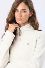 Buzo de polar color crema con cuello alto y cierre frontal parcial. Presenta detalles en cuero en el tirador del cierre y un pequeño bordado en el pecho y en la manga.