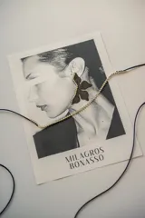 Par de aros dorados con forma de media flor, con detalle de strass negro y gancho de acero quirúrgico.