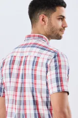 Camisa sport de manga corta con estampa de cuadros, combinando líneas rojas y azules sobre fondo blanco. Posee cuello con botones y cierre frontal abotonado.