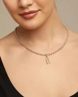 Dije con forma de letra A, elaborado artesanalmente en metal bañado en plata, con diseño inspirado en la estética de clavo característica de la marca.