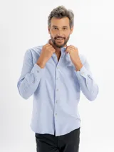 Camisa de corte regular confeccionada en tejido oxford, color azul claro. Presenta cuello con botones, cierre frontal abotonado, mangas largas con puños y un bolsillo frontal en el pecho.