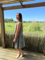 Vestido celeste de lino, sin mangas, con cuello mao y botones de nácar. Presenta varios cortes en su largo, aportando movimiento y un toque moderno a este diseño fresco y elegante.