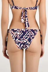 Bombacha de bikini con tiras laterales ajustables, decoradas con borlas colgantes. Presenta un estampado abstracto en tonos azul marino, blanco y naranja.