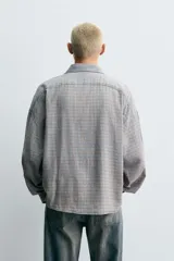 Sobrecamisa de corte relajado confeccionada en tejido de algodón con diseño de cuadros. Presenta cuello solapa, cierre frontal de botones y mangas largas con puños abotonados.