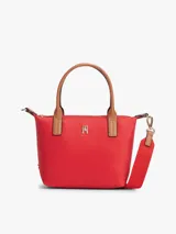 Cartera tote Tommy Hilfiger de nailon rojo, con dos asas superiores en tono tostado y una correa de mano o hombro tejida extraíble. Cuenta con cierre de cremallera superior, compartimento principal e insignia metálica con el monograma TH en el frente.