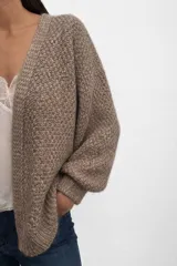 Cardigan de punto abierto con diseño melange, confeccionado en una mezcla de mohair y algodón. Presenta mangas largas con puños ajustados y un tejido de textura marcada.