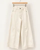 Pantalón wide leg de denim color beige, con tiro alto, cortes frontales verticales y botamanga ancha.