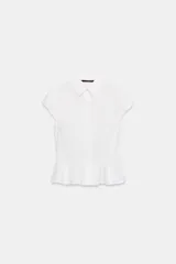 Camisa lisa de algodón blanco, con cuello solapa, manga corta abullonada y bajo en evasé con detalle de peplum. Cierre frontal con botones.