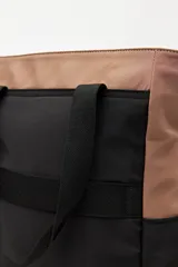 Cartera tote negra con doble asa superior y correa desmontable y regulable. Cuenta con un bolsillo frontal con solapa y cierre, y bolsillos laterales. Presenta pespuntes blancos decorativos y un logo cuadrado en la parte inferior.