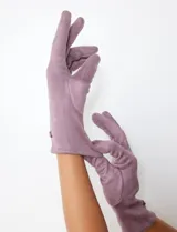 Guante largo de mujer color lila/violeta, confeccionado en material tipo suede (100% poliéster) con interior de terciopelo a tono. Presenta un pequeño detalle de botón o aplique en la muñeca.