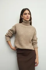 Polera de cuello alto con textura tramada, manga larga con puños acanalados y diseño holgado.