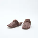 Pantuflas tipo mule color marrón, confeccionadas en material aterciopelado con borde de pelo sintético en la parte superior y suela plana.