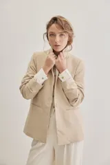 Blazer sastrero de lino color beige, de silueta relajada y líneas clásicas. Incorpora solapas tradicionales, cierre frontal de un botón y bolsillos de vivo.