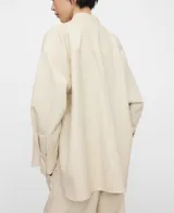 Sobrecamisa de efecto piel color beige, de corte recto y holgado, con cuello mao, manga larga, cierre frontal de botones y un bolsillo aplicado en el pecho.