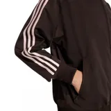 Campera deportiva Adidas Firebird de color marrón con cierre frontal, cuello alto y puños y dobladillo de canalé. Cuenta con las clásicas tres tiras en las mangas y el logotipo del trébol bordado en el pecho.