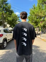 Remera de corte oversize con efecto lavado, color negro, con estampado vertical de cuatro iconos abstractos en la espalda.