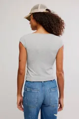 Remera de punto acanalado fino, color gris, de calce ajustado, con escote barco amplio, mangas muy cortas tipo casquillo y largo a la cintura.