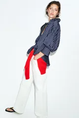 Camisa de corte oversize con estampado de rayas verticales, cuello solapa, escote en pico y mangas abullonadas con puños anchos. Cierre frontal mediante botones.