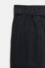 Pantalón de tiro medio color amarillo, con cintura elástica, bolsillos de plastrón en el delantero y pernera holgada que se estrecha hacia el tobillo. Cuenta con cierre frontal de cremallera y botón.