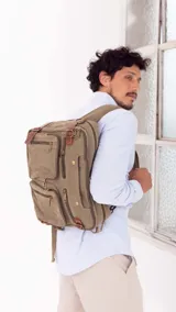 Mochila porta notebook color verde oliva de tela canvas con detalles en cuero marrón. Tiene múltiples bolsillos con cierre y correas ajustables.