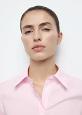 Camisa entallada de popelín de algodón en color rosado, con cuello camisero, manga larga y cierre frontal con botones ocultos bajo tapeta.